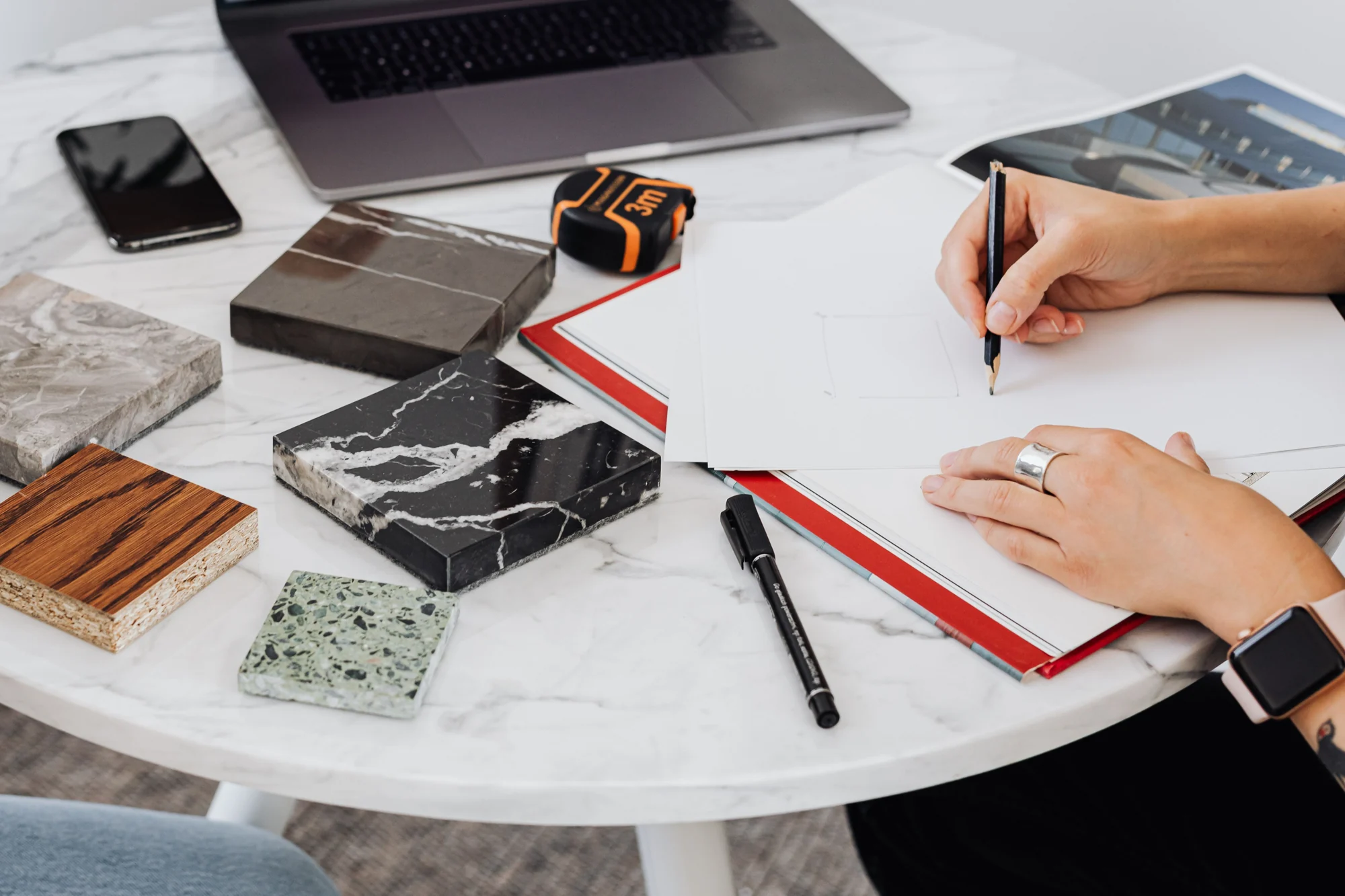 Illustrative planning photo: hands sketching beside material samples